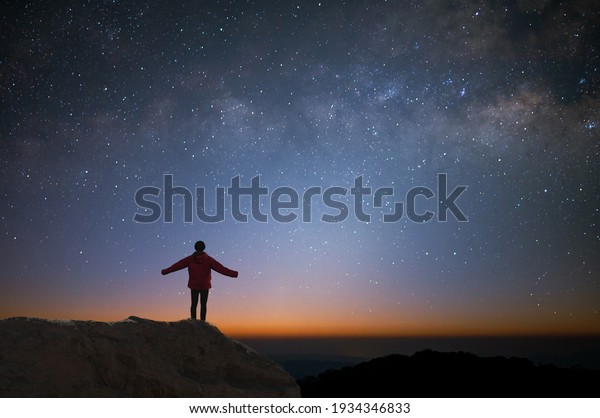Silhouette of\
young traveler and backpacker watched the star and milky way alone\
on top of the mountain. He enjoyed traveling and was successful\
when he reached the\
summit.