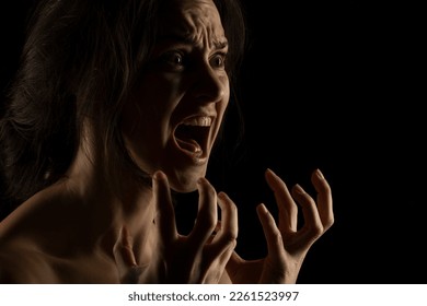 Silhouette of young unhappy screaming woman on black studio background