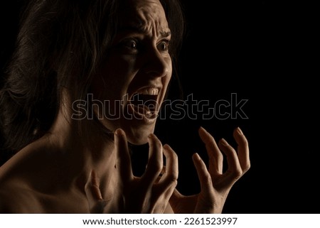 Silhouette of young unhappy screaming woman on black studio background