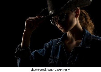 Silhouette of young unknown woman with kowboy hat  and sunglasses on black background