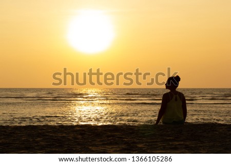Silhouette of a young woman against the backdrop of the sunset and the big sun