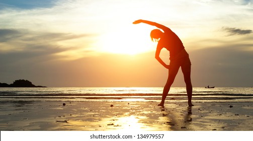 Silhouette young woman, exercise on the beach at sunset.