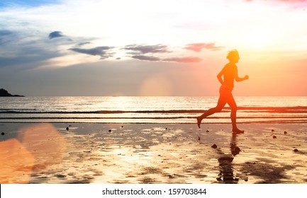 Silhouette of a young woman jogger at sunset on the seashore (with space for text)