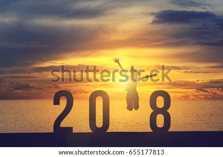 Silhouette young woman jumping on the sea and 2018 years while celebrating new year, happy victory and success concept.