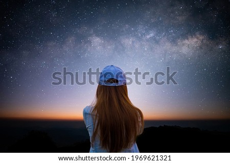 Silhouette of young woman looking beautiful view of night sky and star and milky way alone on top of the mountain. He enjoyed traveling and was successful when he reached the summit.