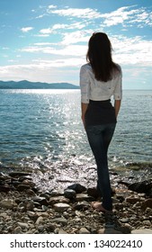 Silhouette of young woman looking at the sea, rear view