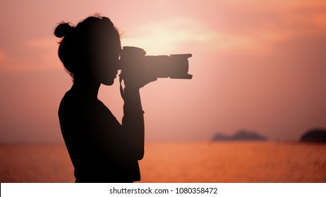 silhouette of young woman photographer, taking pictures of landscape at sunset