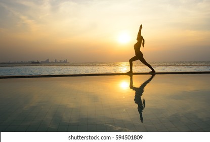 Silhouette young woman practicing pose yoga on swimming pool and the nature beach at sunset or sunrise.  Yoga and  Healthy Concept
 - Powered by Shutterstock