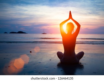 Silhouette young woman practicing yoga on the beach at sunset. - Shutterstock ID 126464135