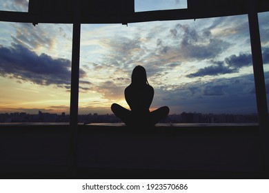 Silhouette of young woman practicing yoga in urban surroundings. Practicing yoga outdoors at sunset with a big city at the background. Healthy, harmony and meditation concept - Powered by Shutterstock