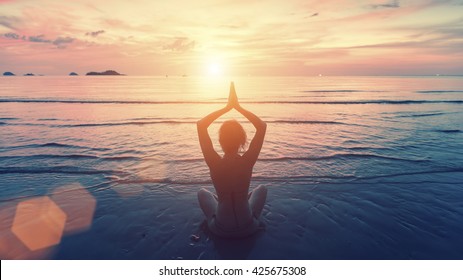 Silhouette young woman practicing yoga on the sunset beach. Tranquility and concentration. - Shutterstock ID 425675308