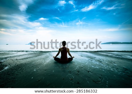Silhouette young woman practicing yoga on the beach