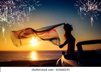 Silhouette Of Young Woman Relaxing At The Beach. Beautiful Woman With Flying Fabric. Fireworks In Sunset Sky. Summer Vacation And Holiday Concept