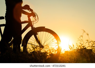 silhouette of young woman riding bike at sunset - Shutterstock ID 472113241