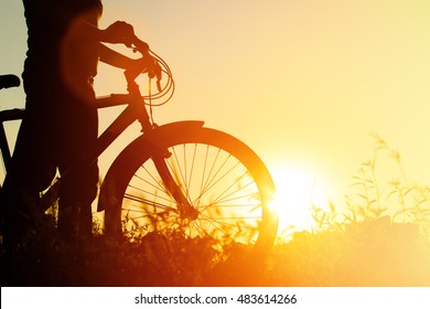 silhouette of young woman riding bike at sunset - Shutterstock ID 483614266
