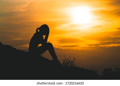 silhouette of a young woman sadly  with the sky at sunset