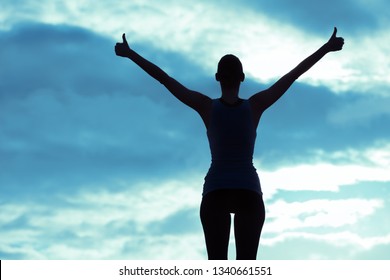 silhouette of young woman with thumbs up feeling positive. 