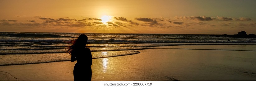 Silhouette of a young woman watching the sunset on the beach,enjoying freedom and life - eople travel wellbeing concept