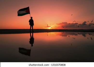 Silhouette Of Youth Holding Up A Palestinian Flag Near Gaza Beach. Gaza - Palestine