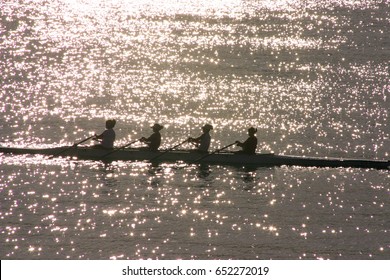 Silhouetted athletes rowing at sunset - Powered by Shutterstock