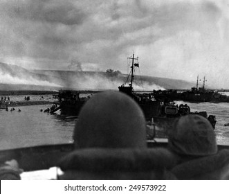 Silhouetted by helmets, view shows two landing craft at Omaha beach on D-Day. Each large ship landed 200 soldiers. June 6, 1944, World War 2.