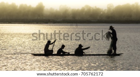 Silhouetted canoe fishing boat throw net fishing Asia.