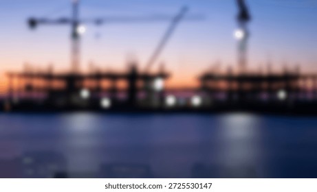 Silhouetted construction cranes and building frames against a vibrant sunset sky, with blurred city lights in the foreground.