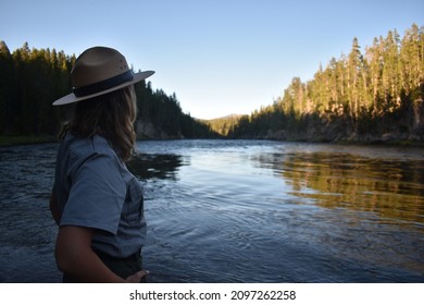 Silhouetted Female Park Ranger Stands Next To The Mighty Yellowstone River - Wyoming, USA