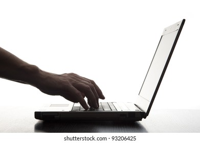 Silhouetted Image Of Someone Typing On A Laptop Computer