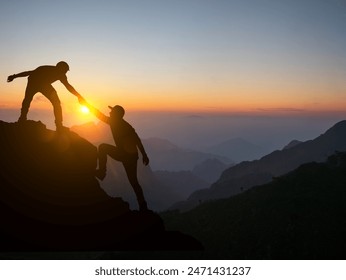 Silhouetted image of two climbers helping each other atop a mountain peak at sunrise, showcasing teamwork and perseverance.