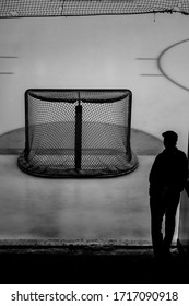 Silhouetted Man Looks At Empty Hockey Net 