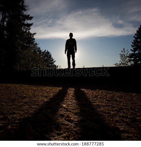 silhouetted man standing on wall in sunset 