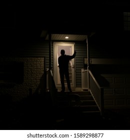 Silhouetted Middle Aged Man Gives Thumbs Up From Porch At Night 