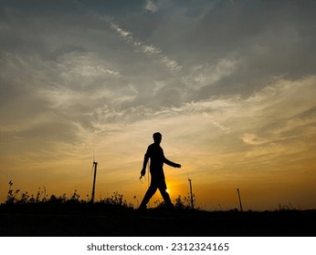 A silhouetted person walking in the time of sunset 