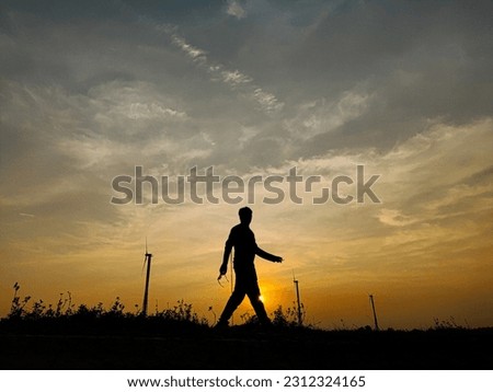 A silhouetted person walking in the time of sunset 