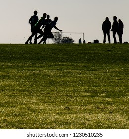 Silhouetted Sunday League Football Players In An English Park