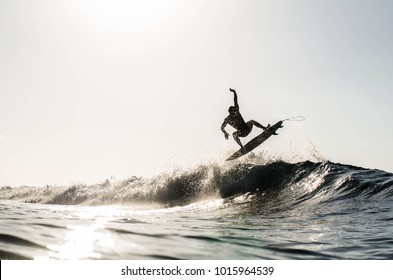 Силуэт серфинг проветривания на волне разбивая на пляже в Пуэрто Рико