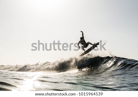 A silhouetted surfing airing on a wave breaking on a beach in puerto rico