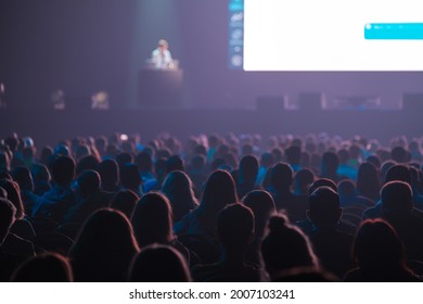 Silhouettes of anonymous people sitting in dark auditorium and listening to speaker talking from stage during business seminar - Shutterstock ID 2007103241