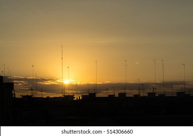 Silhouettes of buildings in at sunset at the city skyline with antennas and cables