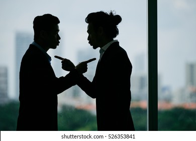 Silhouettes of business partners blaming each other