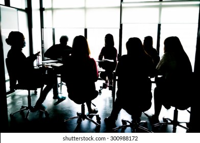 Silhouettes Of Business People Having Board Meeting. Blur Or Defocus Image.