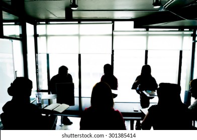 Silhouettes Of Business People Having Board Meeting. Blur Or Defocus Image.