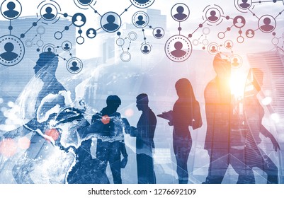 Silhouettes of business people working together over cityscape background with people network sketch and Earth hologram. Toned image Elements of this image furnished by NASA - Shutterstock ID 1276692109