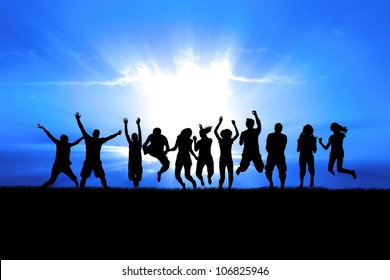 Silhouettes of a celebratory group jump in field of grass, bright sun behind