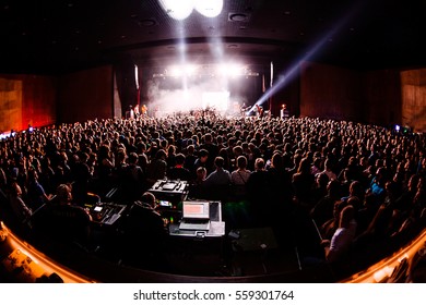 silhouettes of concert crowd in front of bright stage lights  in big club