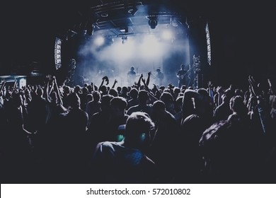 silhouettes of concert crowd in front of bright stage lights. Dark background, smoke, concert  spotlights - Shutterstock ID 572010802