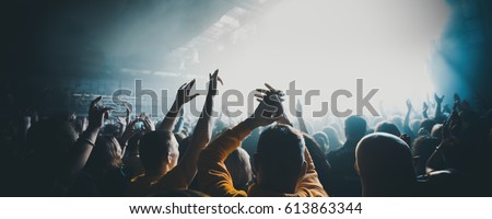 silhouettes of concert crowd in front of bright stage lights. Dark background, smoke, concert  spotlights
