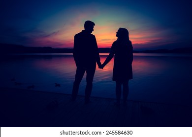 Silhouettes of couple against the sunset sky. Vintage photo.