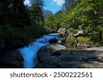 Silhouettes of couple resting around waterfall on trail from Cauterets to lake Lac de Gaube. Pyrenees Natural Park, France